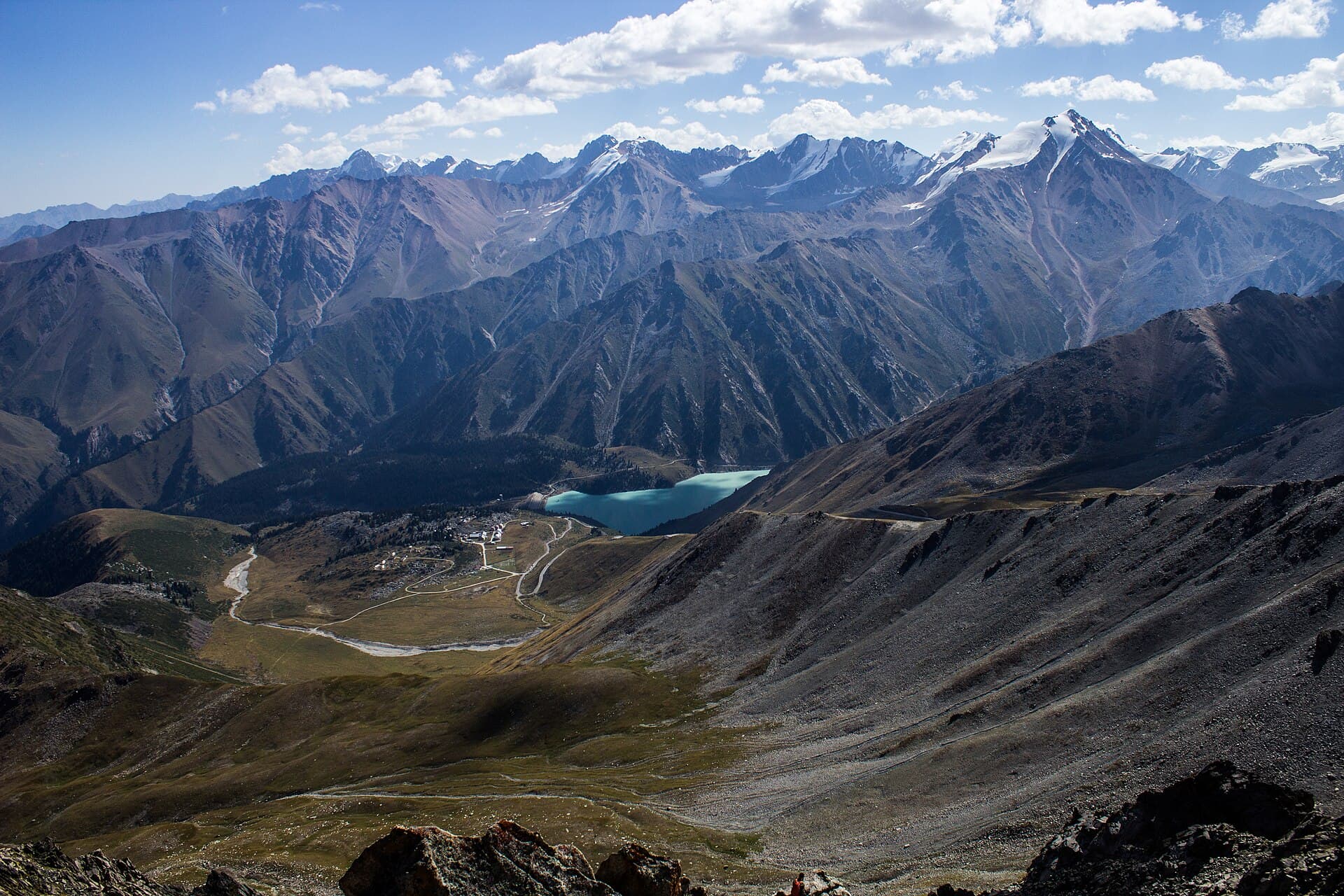 Turquoise Big Almaty Lake in a wide valley beneath snow-capped peaks of the Trans-Ili Alatau near Almaty