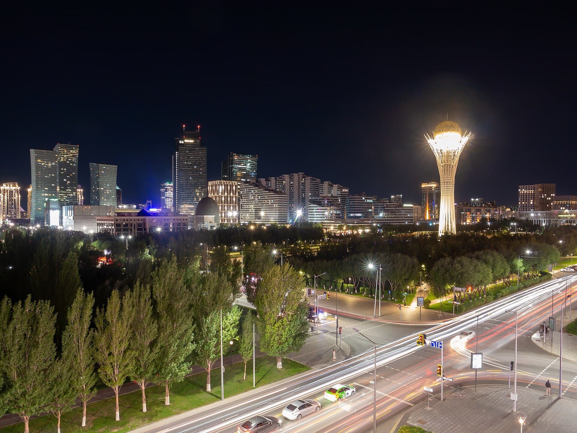 Astana skyline at night with the illuminated Baiterek Tower and light trails on the avenue
