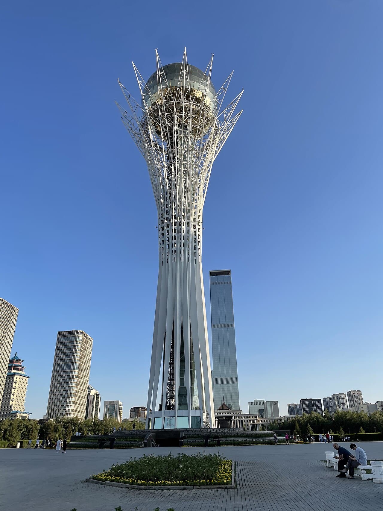 The white lattice Baiterek Tower with its golden sphere rising above Astana against a deep blue sky